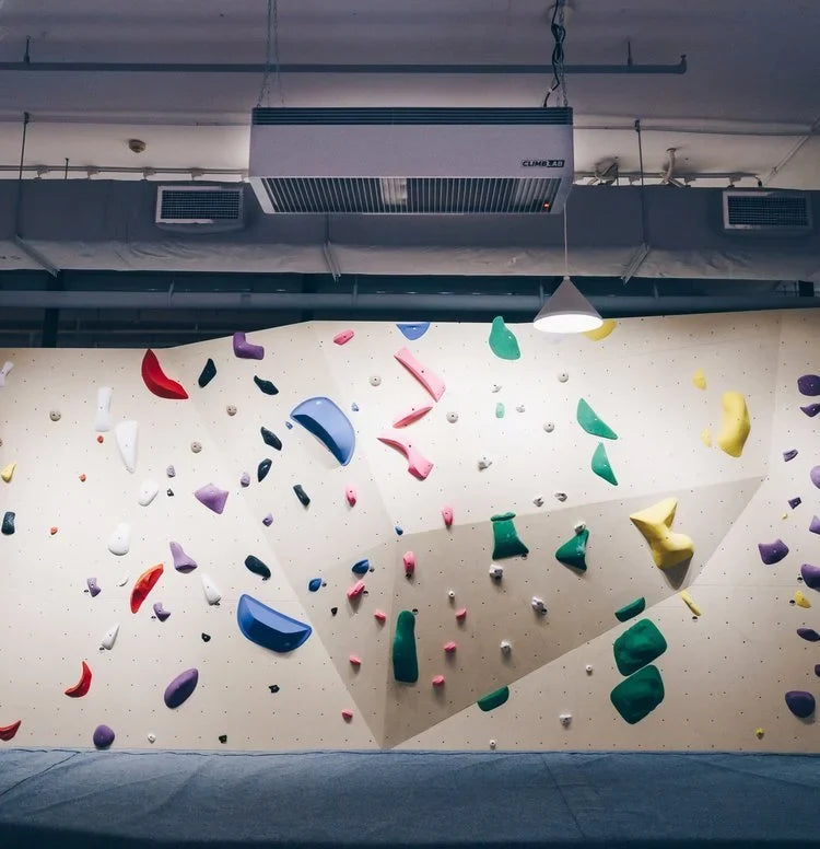 Climber chalking up inside a busy climbing gym with chalk dust hanging in the air under the lights