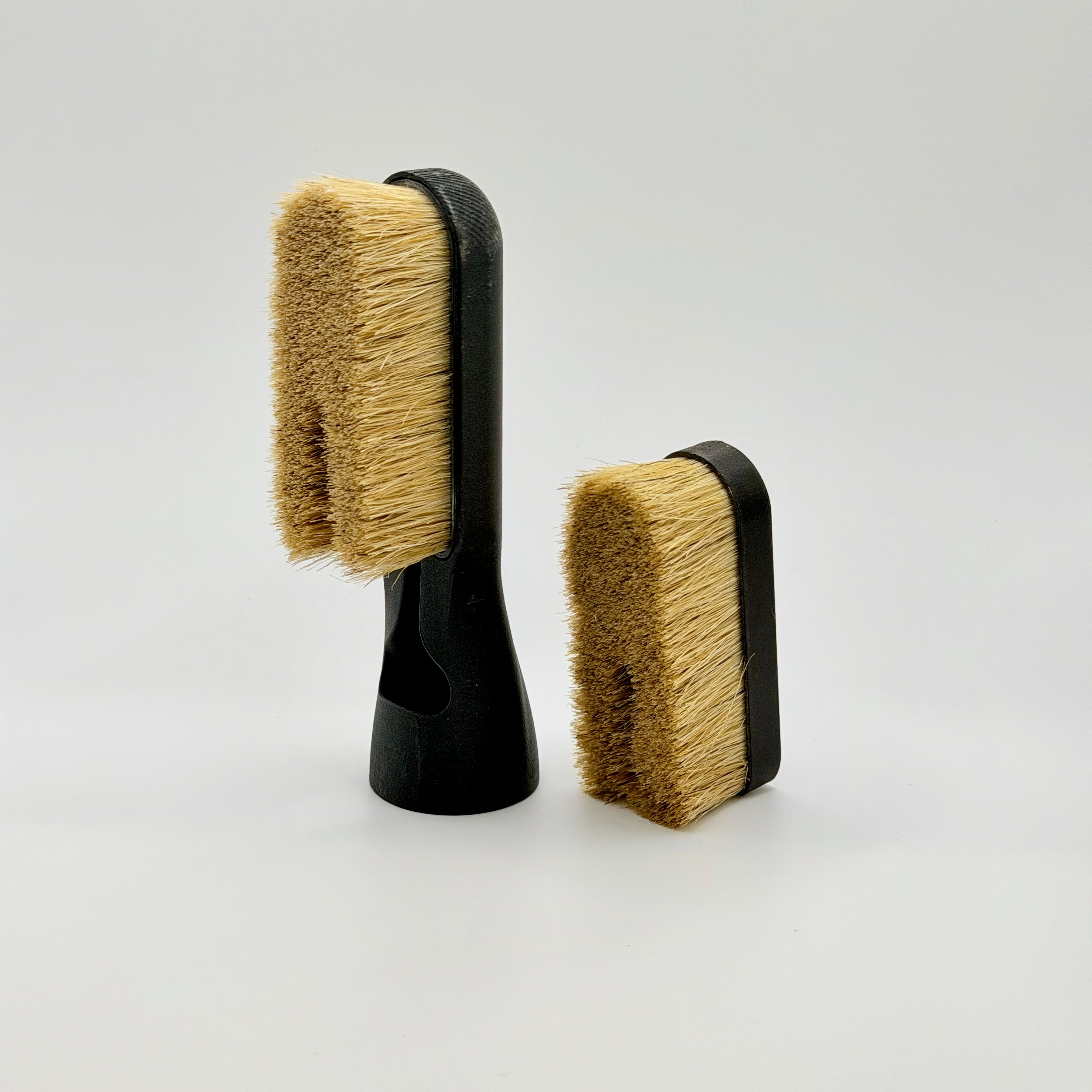 Two climbing brush head with bristle heads and matt black custom brush with air intake on a white background.  Attachment to the Chalk Blaster climbing brush.