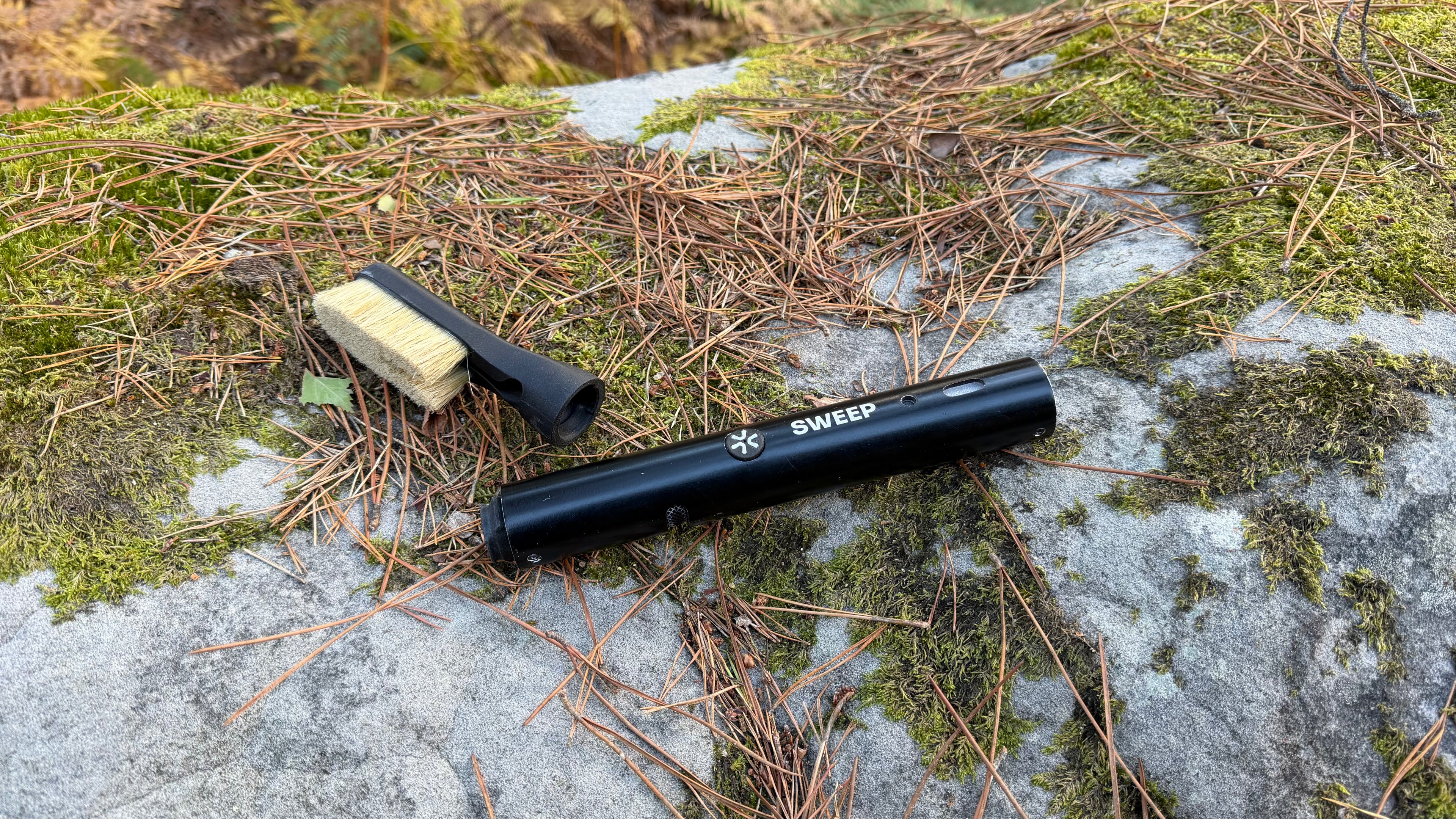 ChalkBlaster and Chalk Blaster Brush head laying outside on top of rock. Showcasing the air intake and blasting function and its locking mechanism.